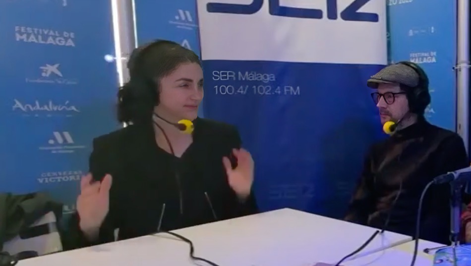 Avelina Prat y Manolo Solo en una entrevista durante el Festival de Málaga, ambos usando auriculares y micrófonos, con un fondo que muestra el logo de SER Málaga.